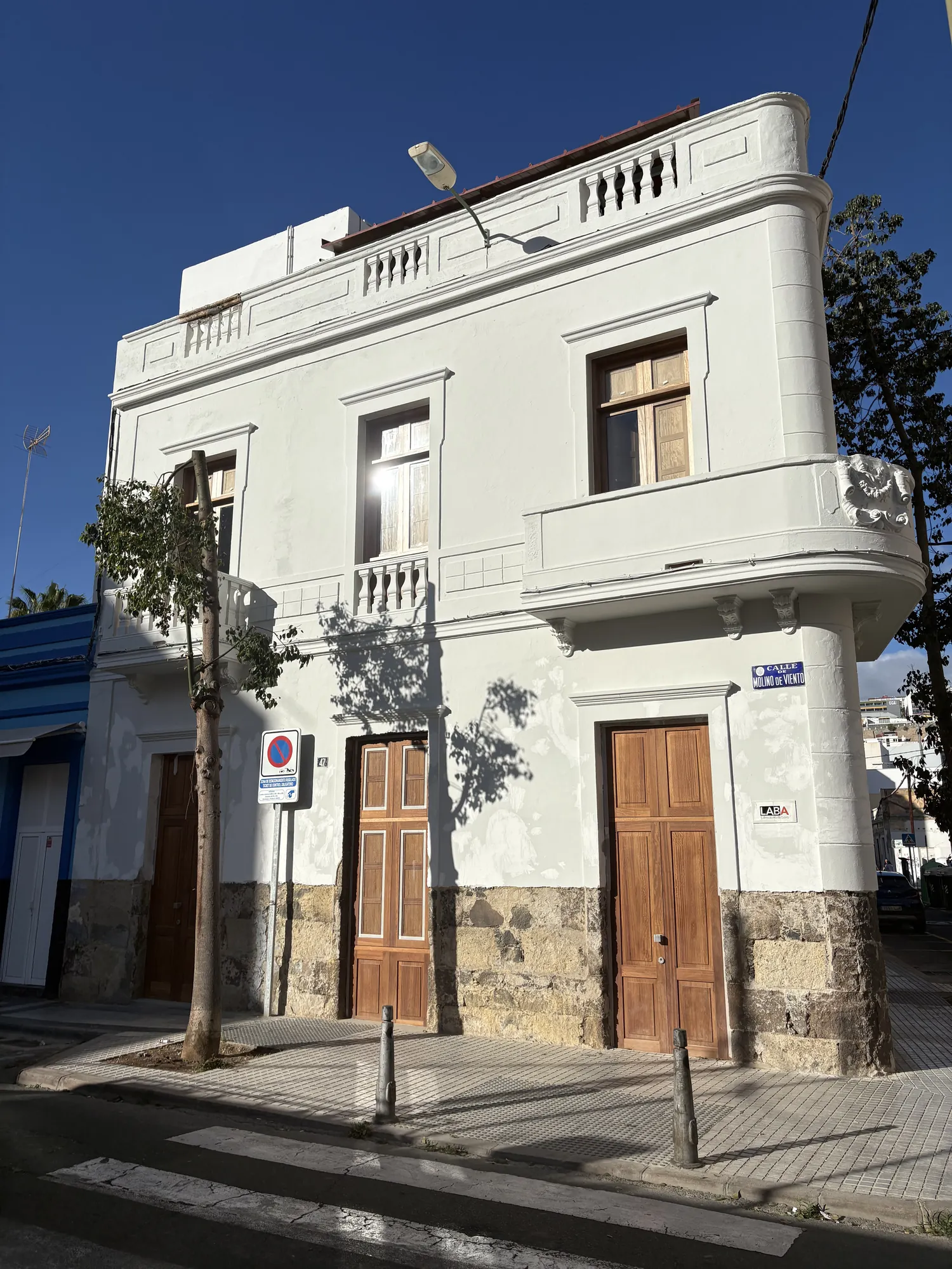 Fachada blanca de Casa M con carpintería de madera y balcón modernista